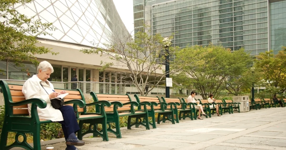 Row of benches along a public walkway in an urban area.